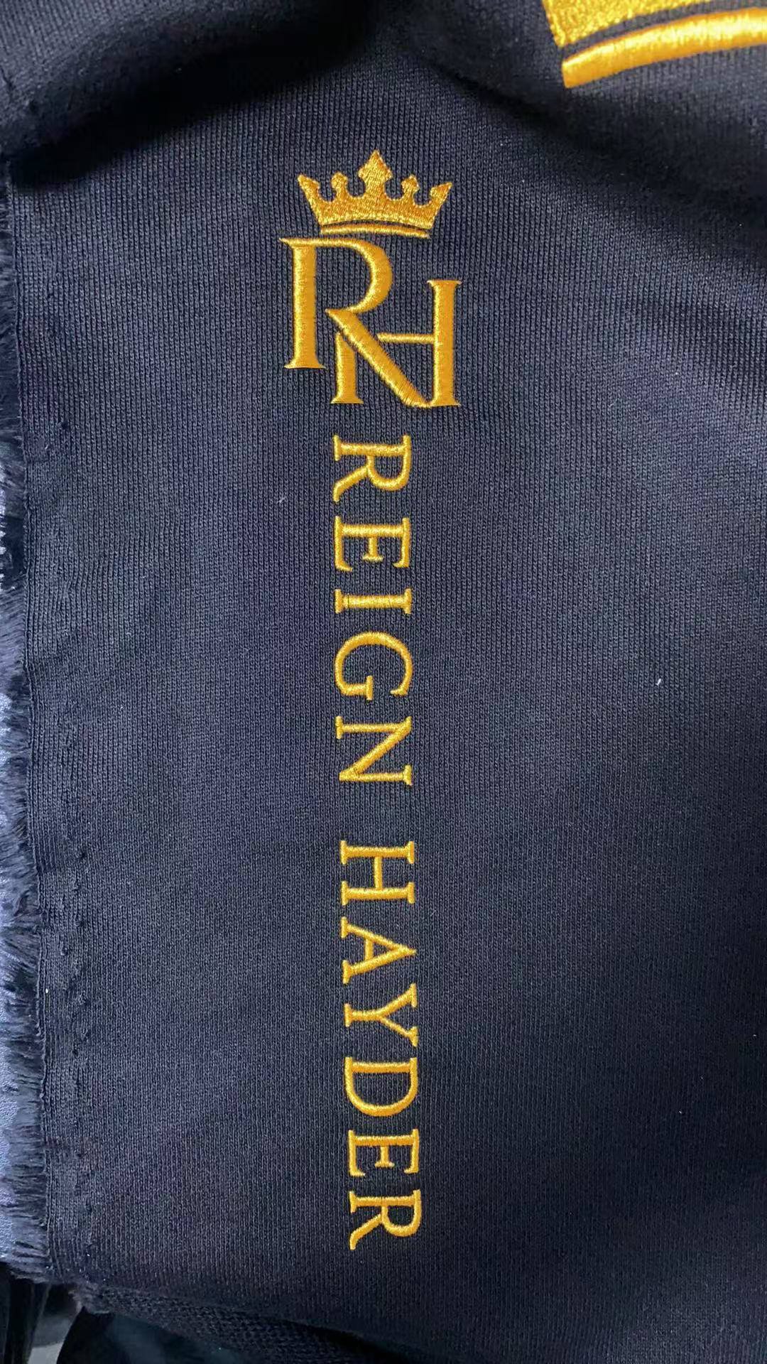 Gold logo embroidery test on dark fabric for custom clothing manufacturing at ASNA Apparel